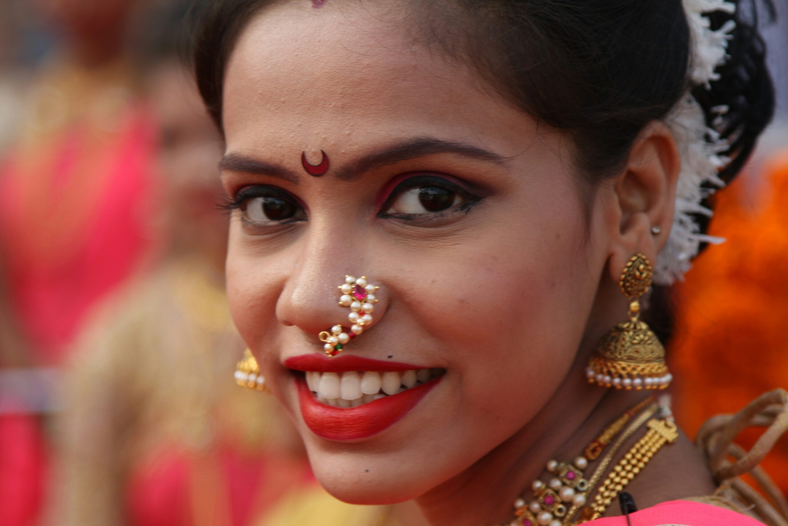 A cheerful woman smiling at a beach wedding, showcasing perfect waterproof makeup