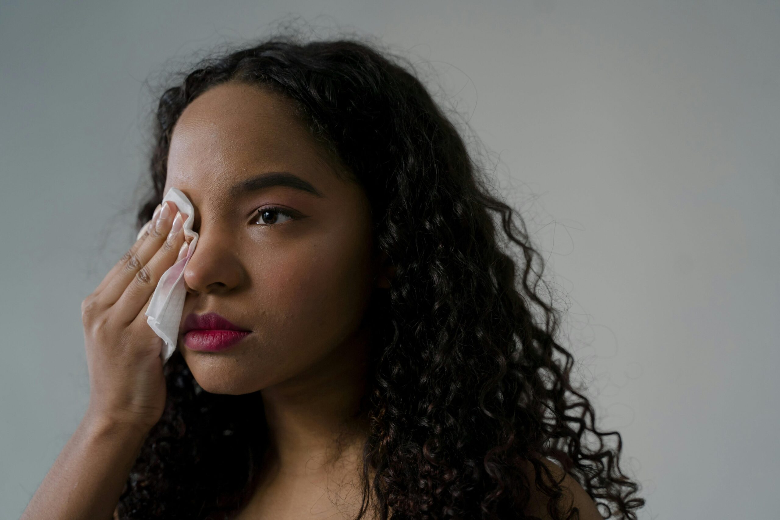 woman wiping sweat off her face with ruined makeup