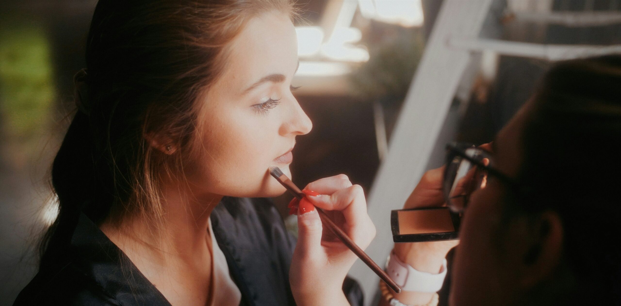 Close-up shot showing detailed steps of applying lipstick using brush and liner.