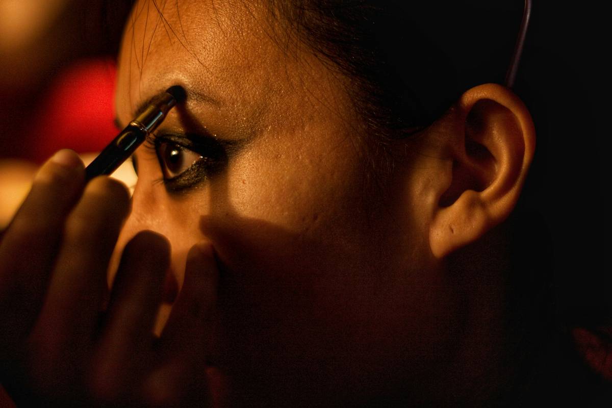 A hand holding a liquid eyeliner pen applying a precise wing tip