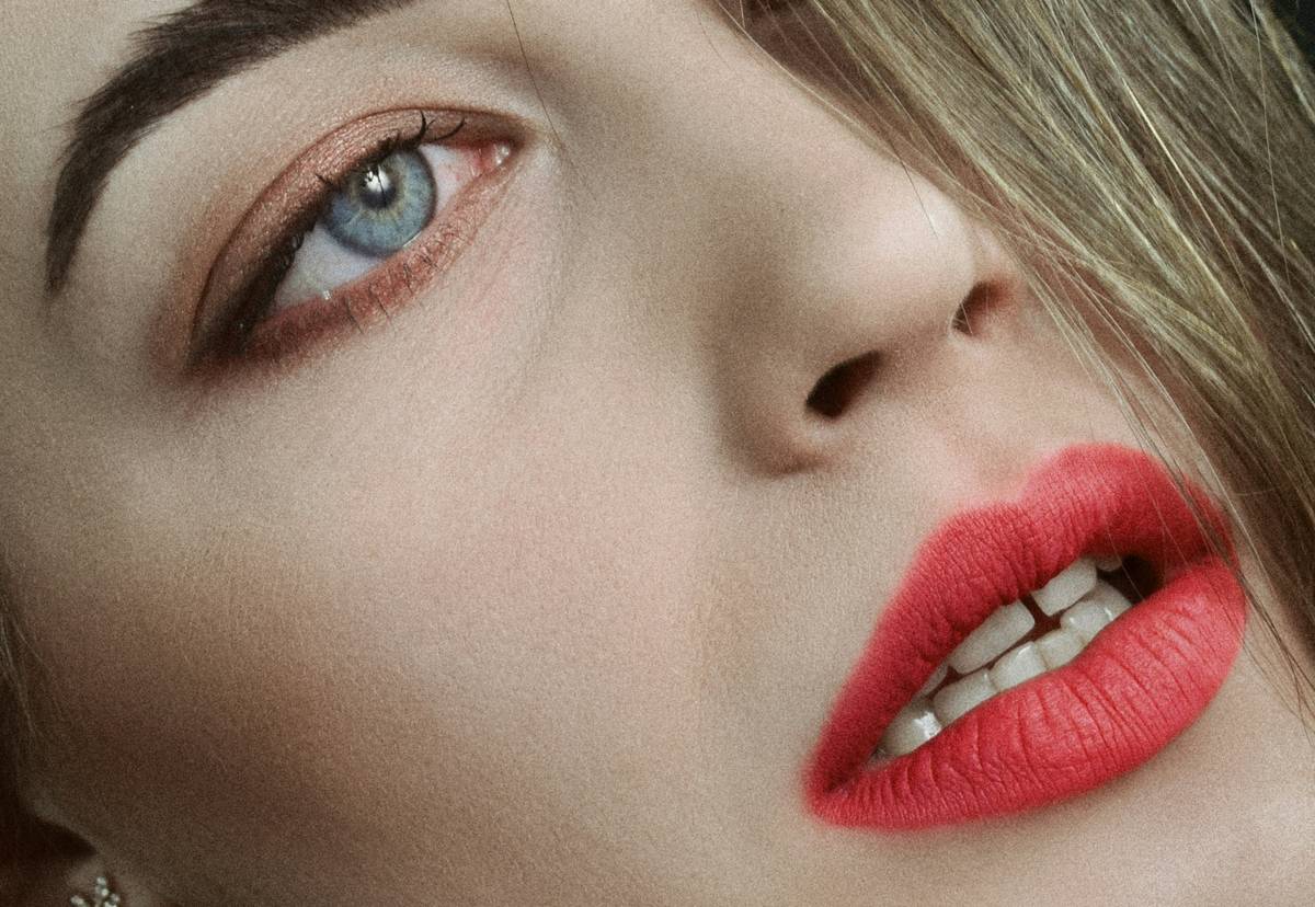A woman confidently smiling with vibrant long-wearing lipstick