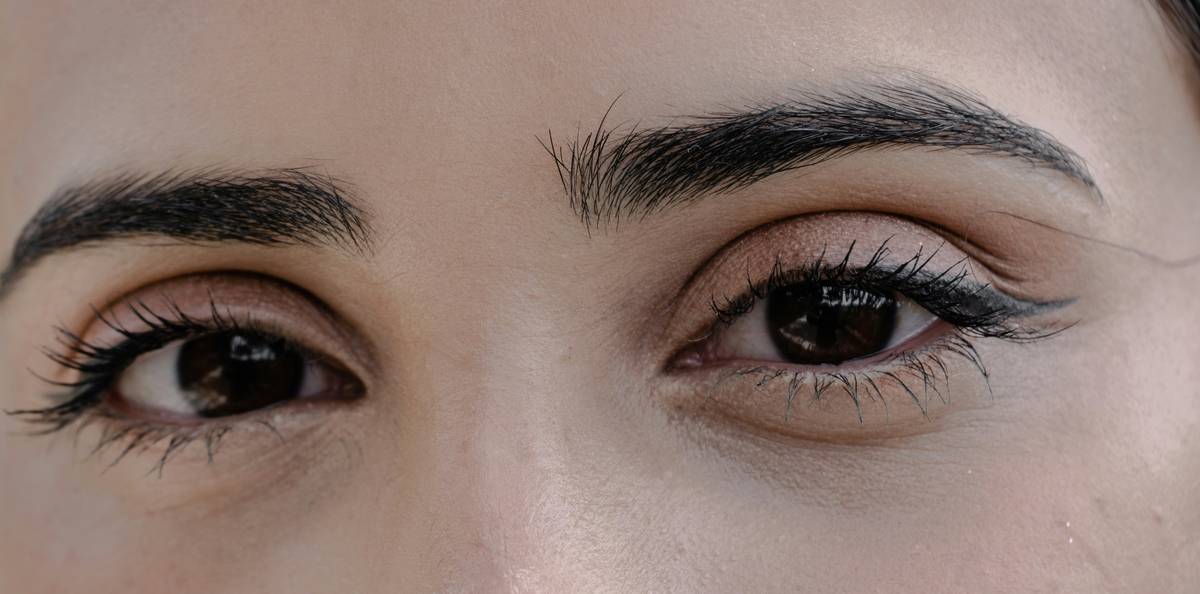 A woman applying waterproof mascara with caption 'Stay flawless no matter what'