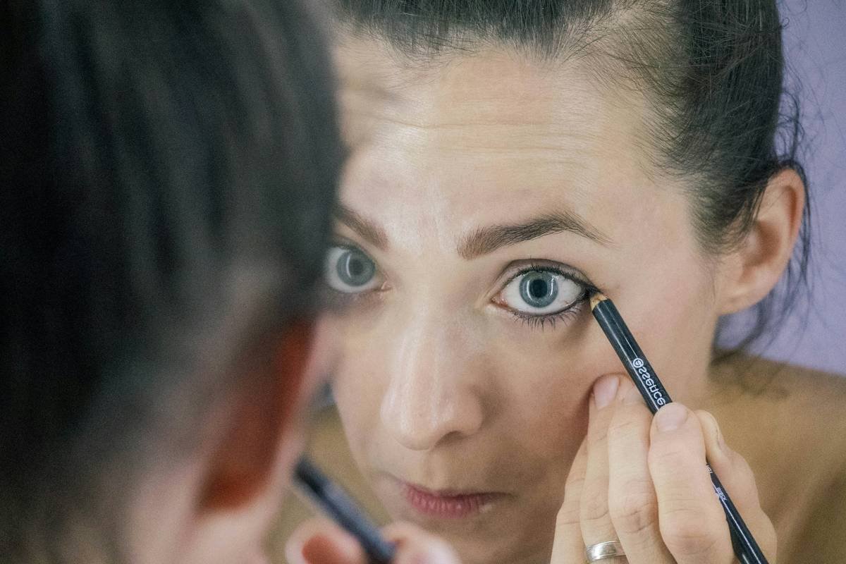 Woman touching her cheek with mascara smudges under eyes