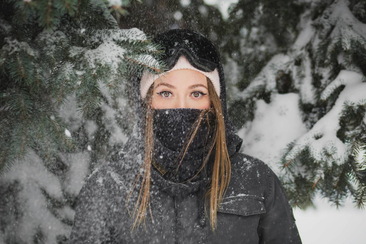 A model holding a setting spray bottle outdoors in snowy weather