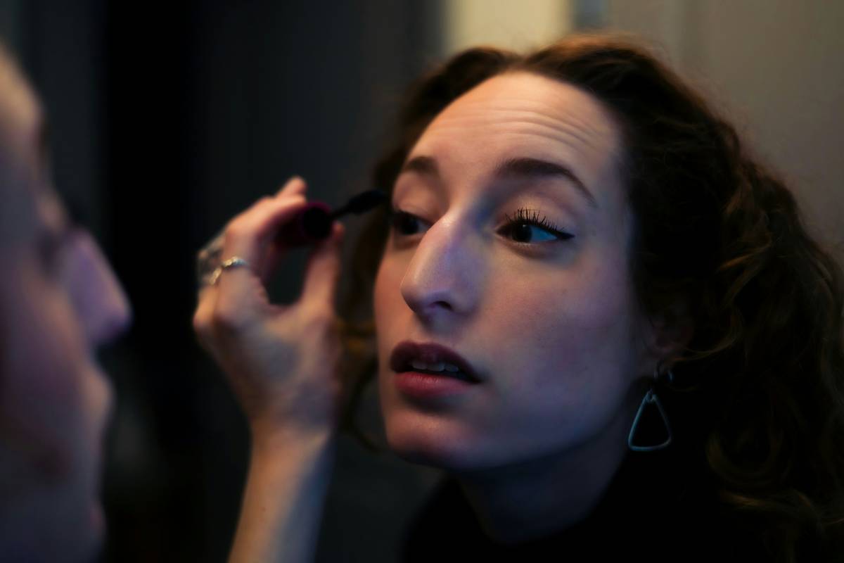 A woman applying waterproof eyeliner confidently while smiling.