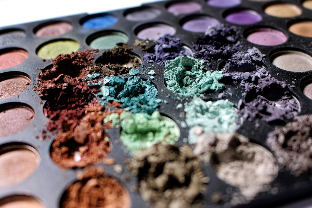 Infographic showing key ingredients in durable vs. non-durable eyeshadow palettes: film formers, binders, and water-repellent coatings highlighted.