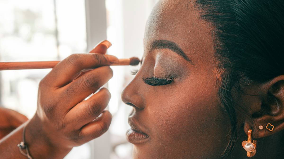 Model applying waterproof face powder with a fluffy brush for smudge-proof coverage